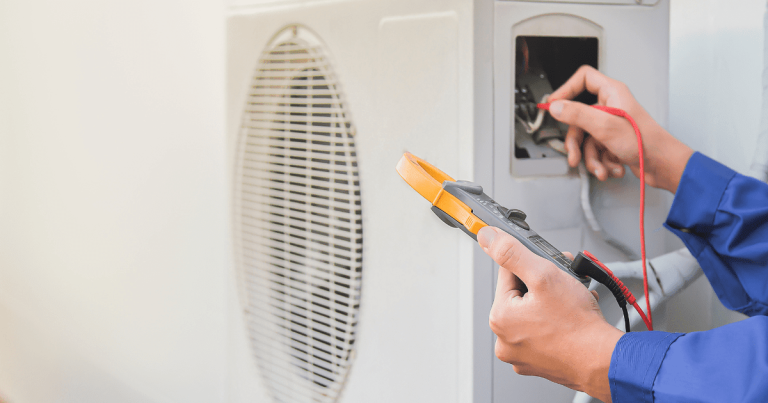 Technician performing AC maintenance, using tools to test and inspect an outdoor air conditioning unit.