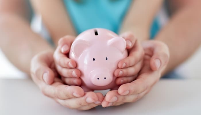 Parent And Child Holding Piggy Bank